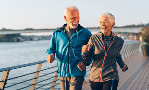 Active senior couple jogging by the river, smiling and enjoying the outdoors.