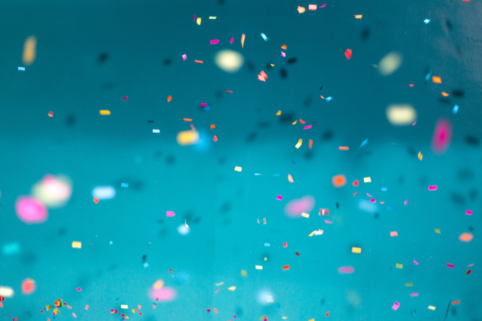 Colorful confetti floating against a blue background during a celebration.